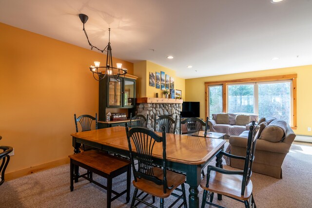 carpeted dining space with a baseboard radiator, recessed lighting, baseboards, a stone fireplace, and a chandelier