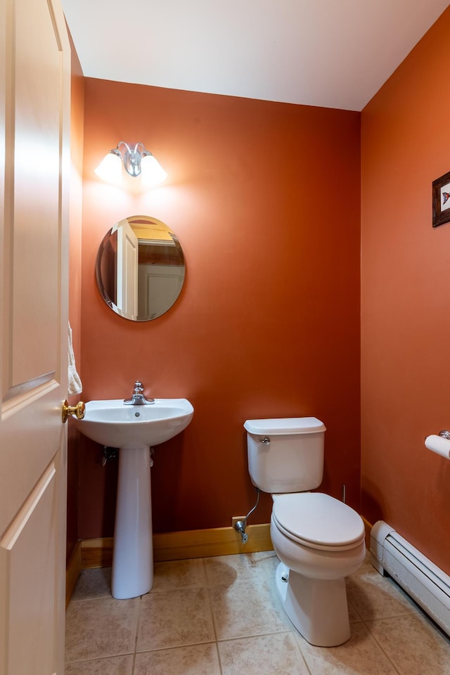 half bath featuring toilet, baseboards, baseboard heating, and tile patterned floors