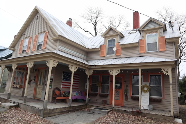 view of front of home featuring a porch, a chimney, metal roof, and a standing seam roof