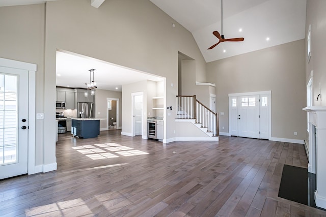 entryway featuring high vaulted ceiling, beverage cooler, ceiling fan, dark wood-style flooring, and stairway