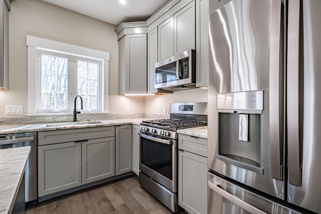 kitchen with appliances with stainless steel finishes, a sink, dark wood-style floors, gray cabinets, and recessed lighting
