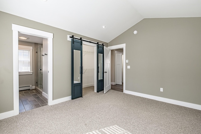 unfurnished bedroom featuring baseboard heating, light colored carpet, a spacious closet, a barn door, and lofted ceiling