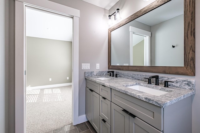 full bath featuring baseboards and double vanity