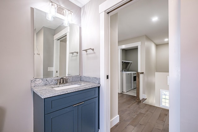 bathroom featuring wood finished floors, separate washer and dryer, vanity, and baseboards