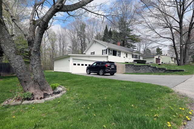 view of property exterior featuring asphalt driveway, a yard, and an attached garage