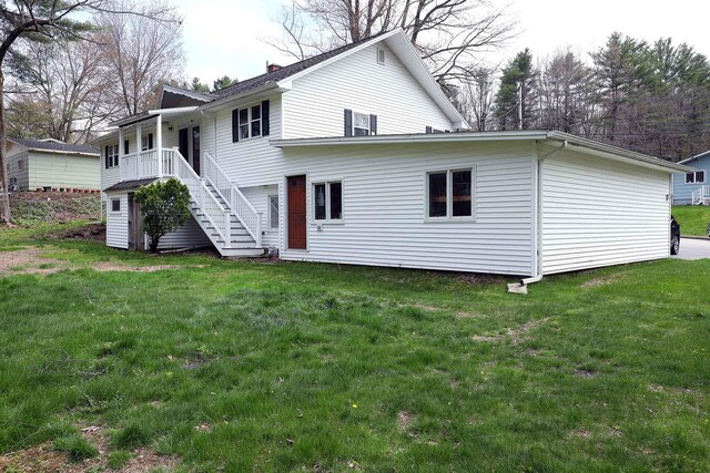 rear view of house with stairs, a lawn, and a chimney