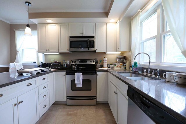 kitchen featuring stainless steel appliances, a sink, white cabinets, dark stone counters, and ornamental molding
