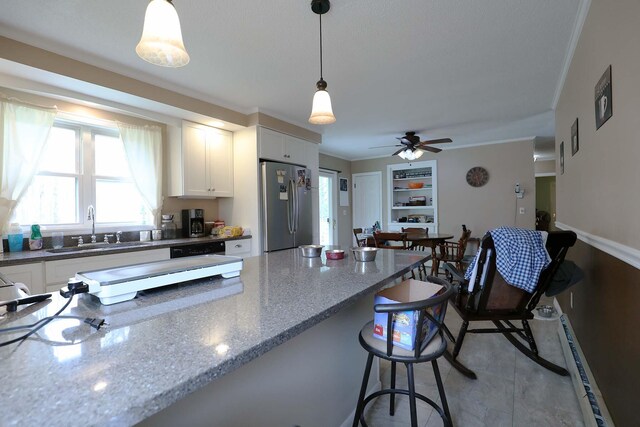 kitchen featuring freestanding refrigerator, a sink, plenty of natural light, white cabinetry, and ornamental molding