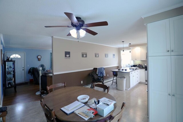 dining area with a ceiling fan, crown molding, a baseboard heating unit, and light floors