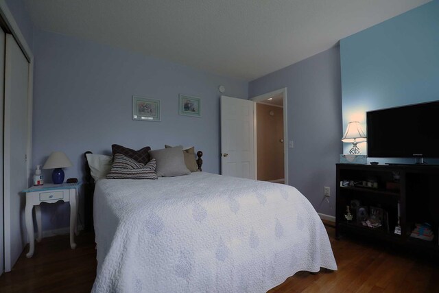 bedroom with dark wood finished floors, baseboards, and a closet