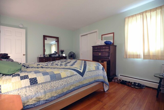 bedroom featuring a baseboard radiator, hardwood / wood-style floors, and a closet
