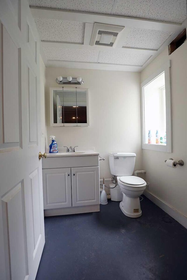 bathroom with toilet, vanity, and baseboards