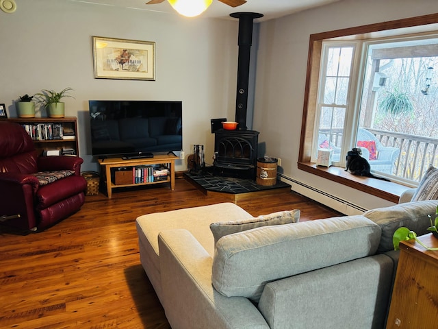 71 Reynolds Rd, Brooks, ME 04921 - living room with a baseboard radiator, a wood stove, healthy amount of natural light, and a ceiling fan