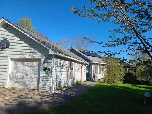 71 Reynolds Rd, Brooks, ME 04921 - view of home's exterior featuring roof mounted solar panels, a yard, and a garage