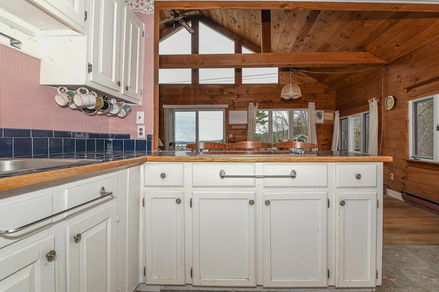 676 S High St, Bridgton, ME 04009 - kitchen with a peninsula, plenty of natural light, white cabinetry, and wood walls