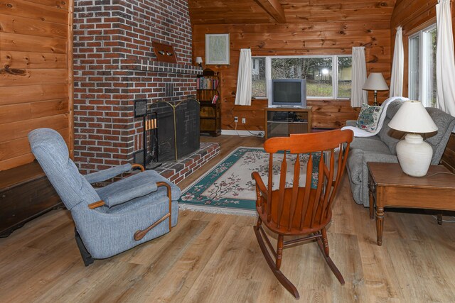 676 S High St, Bridgton, ME 04009 - living area with wood walls, wood finished floors, a fireplace, and vaulted ceiling with beams