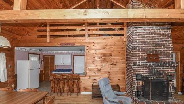 676 S High St, Bridgton, ME 04009 - living area featuring light wood finished floors, wood ceiling, a fireplace, wood walls, and lofted ceiling