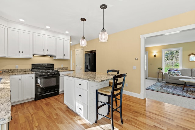 4 Geary Way, Falmouth, ME 04105 - kitchen featuring black appliances, white cabinets, light wood-style floors, a breakfast bar, and a center island