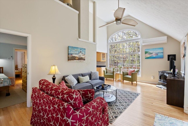 25 Sawmill Ln, Ogunquit, ME 03907 - living area with a wall unit AC, a wood stove, a ceiling fan, wood finished floors, and high vaulted ceiling