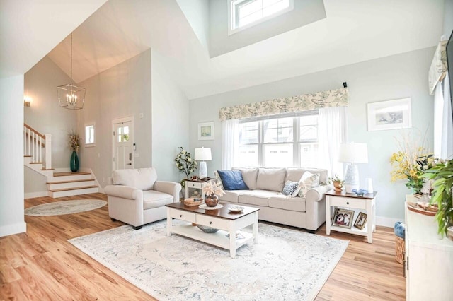 10 Haleys Ct Unit 22, Wells, ME 04090 - living room with a towering ceiling, a chandelier, light wood-style floors, stairway, and baseboards