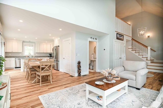 10 Haleys Ct Unit 22, Wells, ME 04090 - living room with light wood-style floors, stairs, a chandelier, a towering ceiling, and baseboards