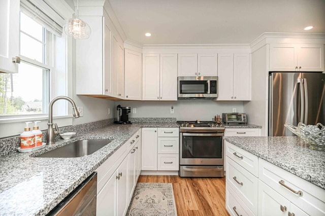 10 Haleys Ct Unit 22, Wells, ME 04090 - kitchen with appliances with stainless steel finishes, a sink, white cabinets, light wood-style flooring, and light stone counters