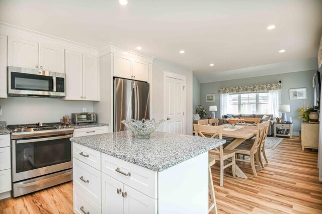 10 Haleys Ct Unit 22, Wells, ME 04090 - kitchen with stainless steel appliances, light wood-style floors, white cabinets, a kitchen island, and light stone countertops