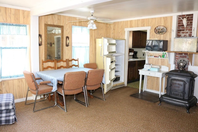 68 Salmon Rd, Madison, ME 04950 - carpeted dining room featuring a wood stove, wood walls, and ceiling fan