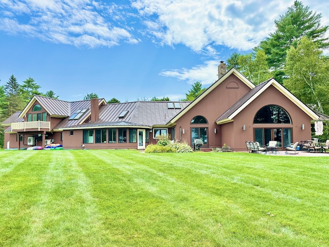 129 Loon Call Dr, Belgrade, ME 04917 - back of property with a standing seam roof, a chimney, a patio area, and a yard