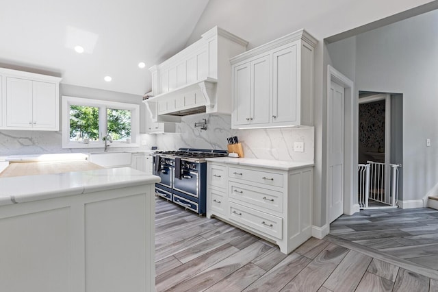 129 Loon Call Dr, Belgrade, ME 04917 - kitchen with double oven range, vaulted ceiling, white cabinets, a sink, and tasteful backsplash