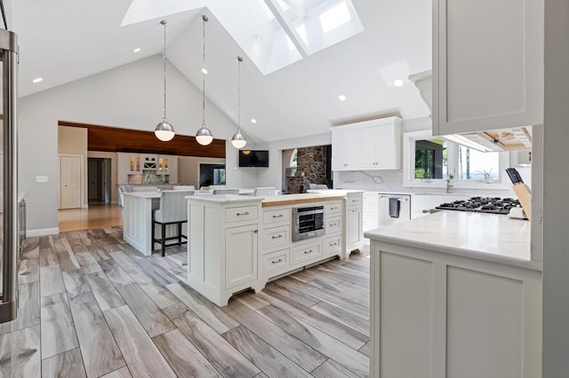 129 Loon Call Dr, Belgrade, ME 04917 - kitchen featuring a skylight, stainless steel appliances, high vaulted ceiling, white cabinets, and a center island