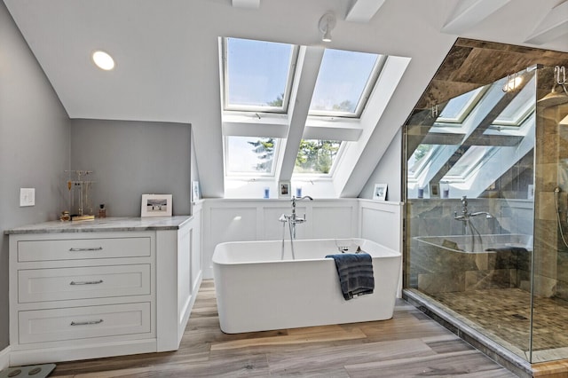 129 Loon Call Dr, Belgrade, ME 04917 - bathroom featuring a skylight, a shower stall, a freestanding bath, and wood finished floors