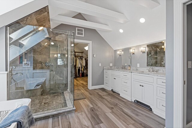 129 Loon Call Dr, Belgrade, ME 04917 - full bathroom featuring a stall shower, double vanity, a walk in closet, baseboards, and wood finished floors
