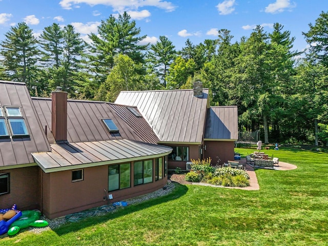 129 Loon Call Dr, Belgrade, ME 04917 - back of property with a standing seam roof, a chimney, an outdoor fire pit, and metal roof