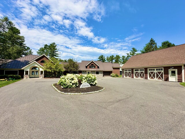129 Loon Call Dr, Belgrade, ME 04917 - view of front of house with stone siding, a standing seam roof, metal roof, and driveway