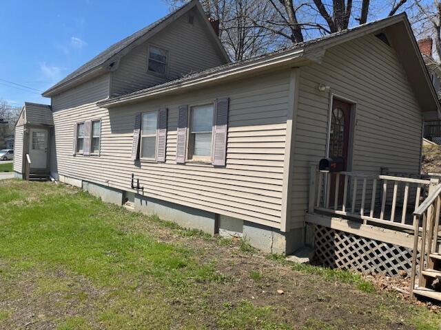 view of home's exterior with a wooden deck and a lawn