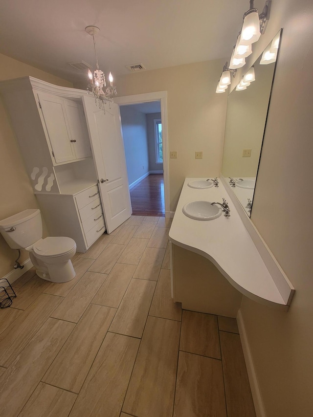 239 Pierce Rd Unit 2B, Brewer, ME 04412 - bathroom featuring toilet, double vanity, a chandelier, wood finish floors, and baseboards