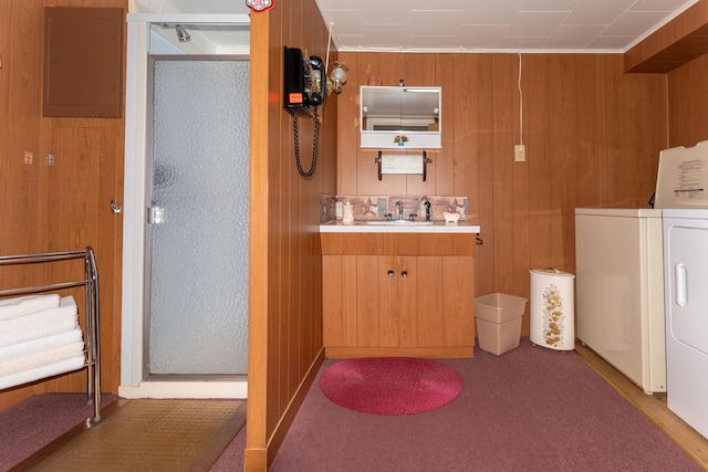 laundry room featuring washer and dryer, electric panel, and wooden walls
