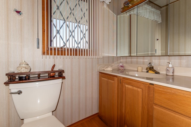 bathroom featuring wallpapered walls, toilet, and vanity
