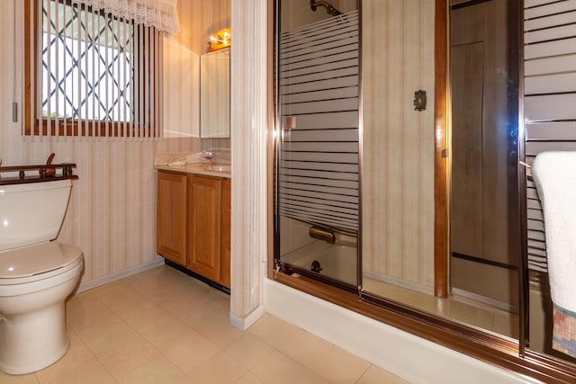 bathroom with wallpapered walls, toilet, bath / shower combo with glass door, baseboards, and vanity