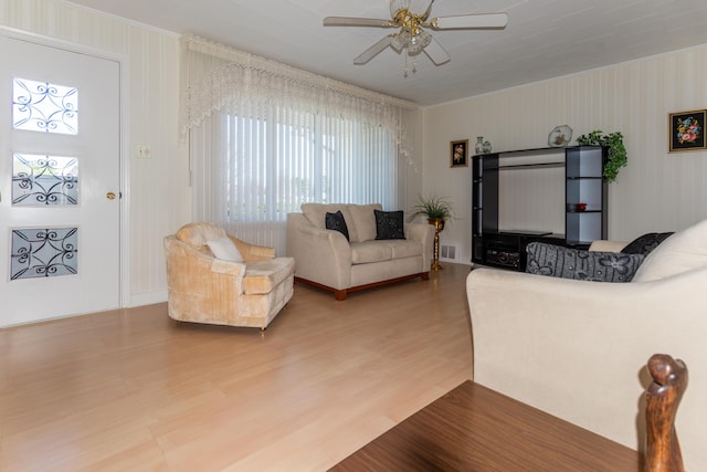 living room featuring ceiling fan, wood finished floors, healthy amount of natural light, and ornamental molding