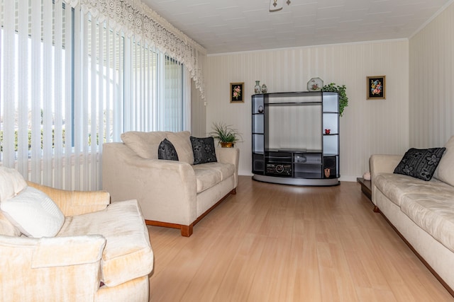 living area featuring healthy amount of natural light, wood finished floors, and crown molding