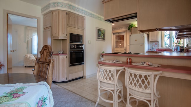 kitchen with black appliances, light tile patterned floors, and a kitchen bar