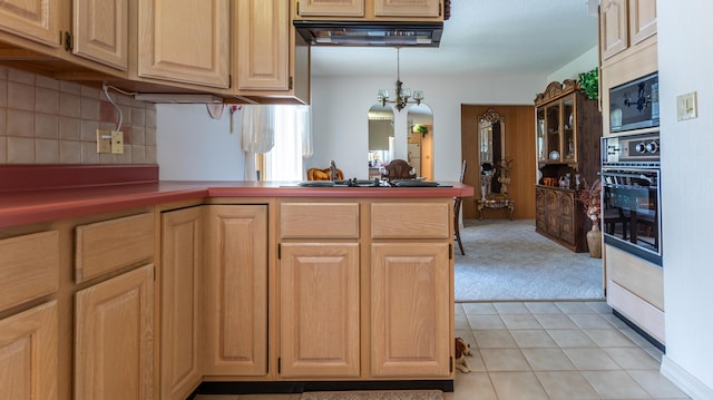kitchen with black oven, a peninsula, built in microwave, tasteful backsplash, and a chandelier