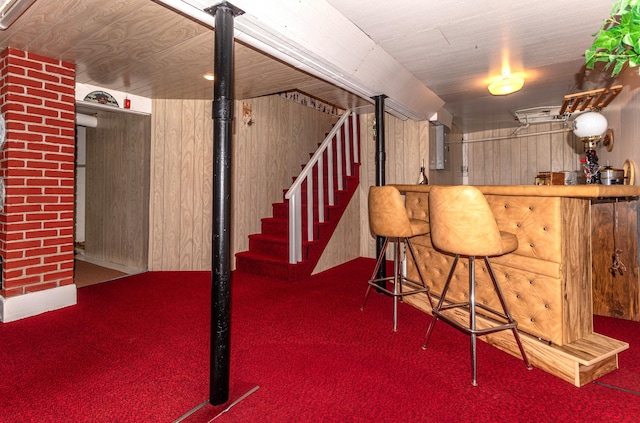 indoor dry bar with carpet flooring, stairway, and wood walls