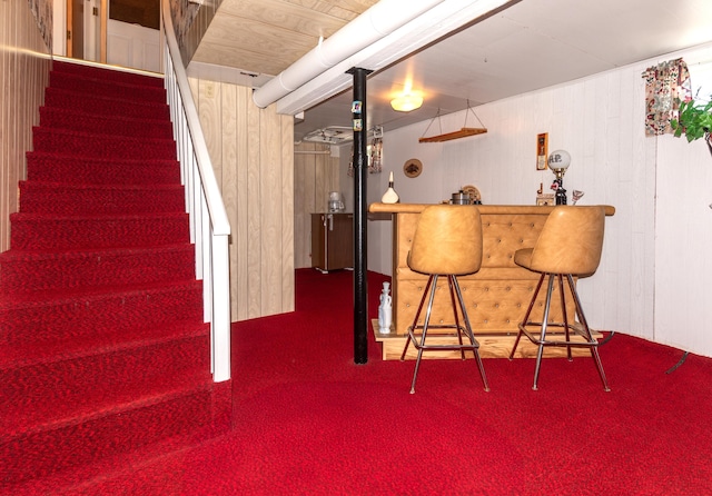indoor dry bar featuring stairs, wooden walls, and carpet floors