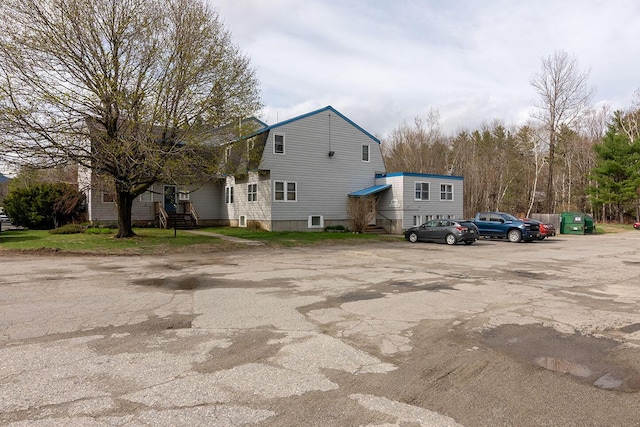 view of home's exterior with a gambrel roof and uncovered parking