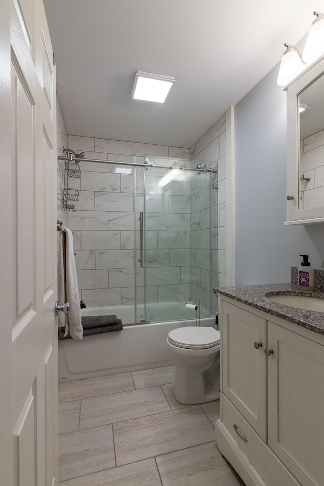 full bath with toilet, vanity, and combined bath / shower with glass door
