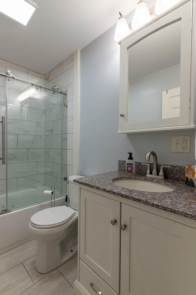 full bathroom featuring toilet, bath / shower combo with glass door, and vanity