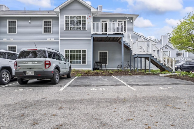 rear view of house with stairs and uncovered parking
